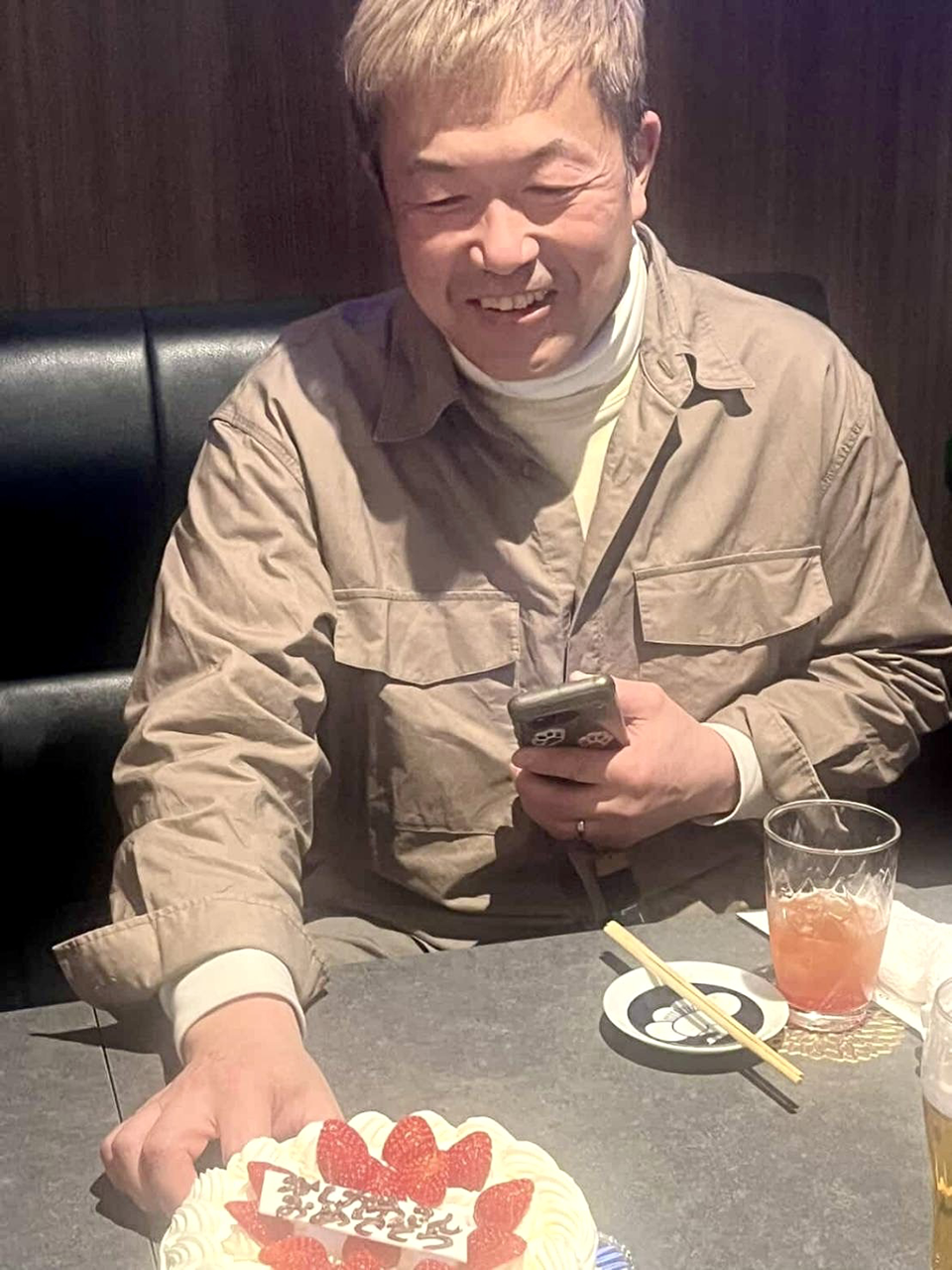 お祝いのケーキを前にして笑顔溢れる店主柏川の写真